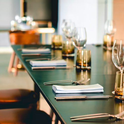 Empty glasses, plate, fork, knife on the table served for dinner in the modern restaurant