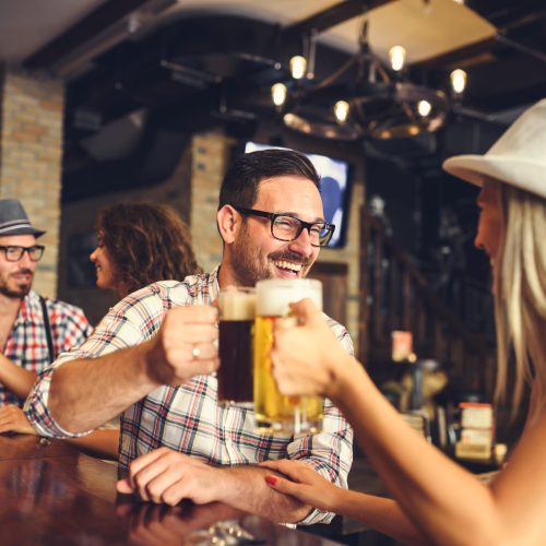 Young cheerful people in the beer pub drinking and having good t